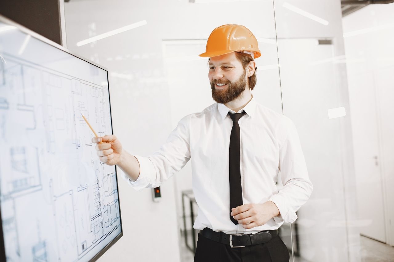 Professional engineer explains blueprint on digital screen in modern office.
